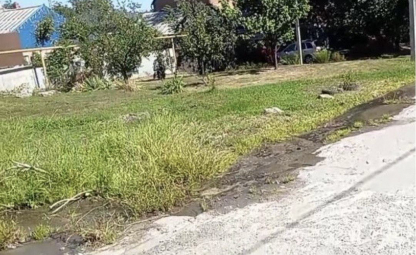 Утечка воды по дороге, которая разрушает асфальт и подмывает опору электропередачи в Шахтах